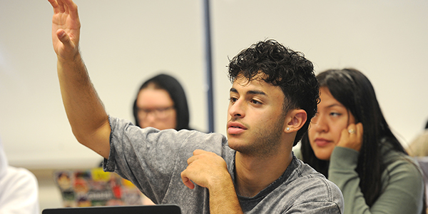 A student raising their hand in class.